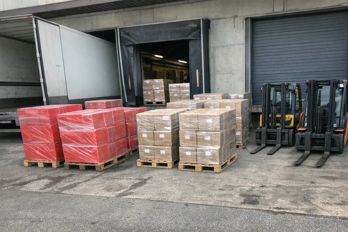 Palletised home safety kit cartons staged at a Gothenburg loading dock with a truck trailer at the bay and no people present.